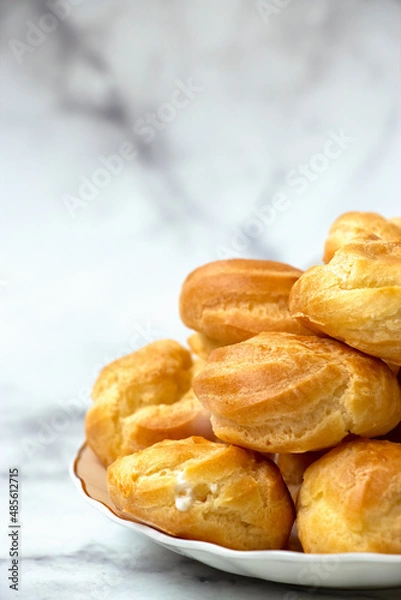Obraz Homemade profiteroles stuffed with whipped cream On marble light background.