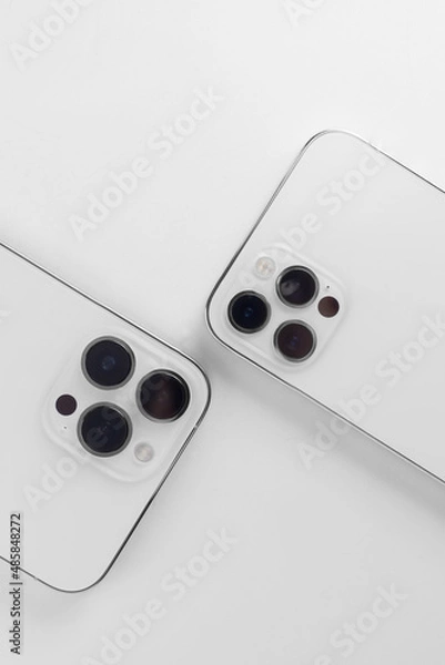 Fototapeta  white smartphones on a white background lie with the cameras up. Iphone 12 pro, iphone 13 pro max