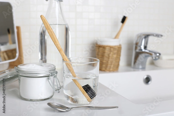 Fototapeta Soak a toothbrush in solution of  white vinegar, water and baking soda on the bathroom sink close up.