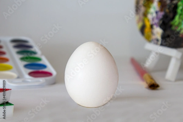 Fototapeta White Easter egg on a watercolor background. Simple holiday composition. Symbolism of the Easter egg festival concept. Art work, handmade, creativity with children for decoration for Easter