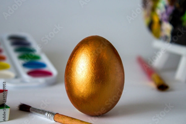Fototapeta Golden Easter egg on a watercolor background. Simple holiday composition. Symbolism of the Easter egg festival concept. Art work, handmade, creativity with children for decoration for Easter