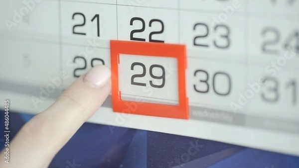 Fototapeta Close-up of a woman's finger moves the date pointer on the calendar