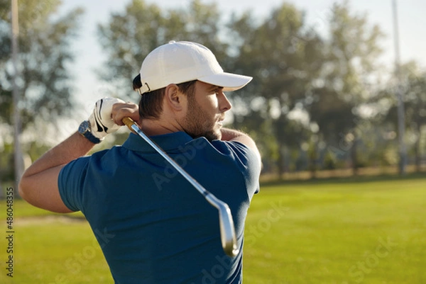 Fototapeta Golfer playing golf on green field at sunny day