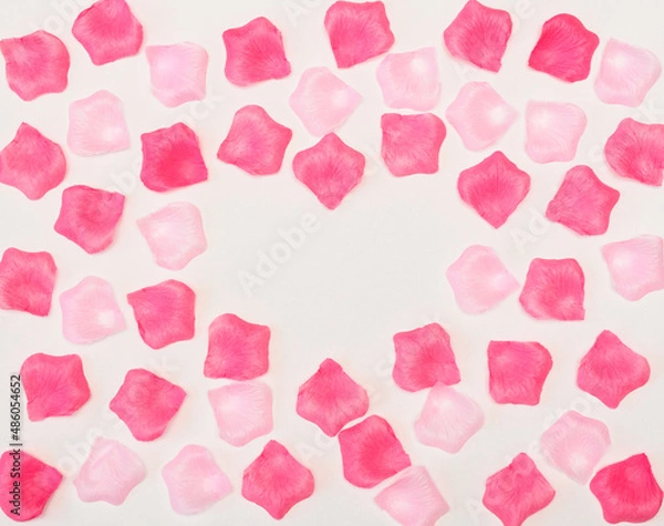 Fototapeta Many pink petals on white background with heart shaped copy space in the middle. Valentines day, love concept. Flat lay style
