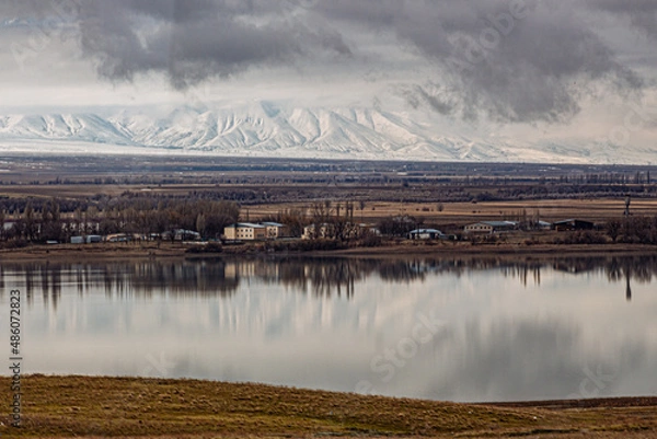 Fototapeta amazing mountains under grey clouds and reflection in mountain lake