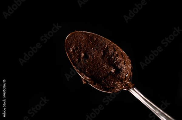 Obraz Spoon with melted chocolate on a dark background