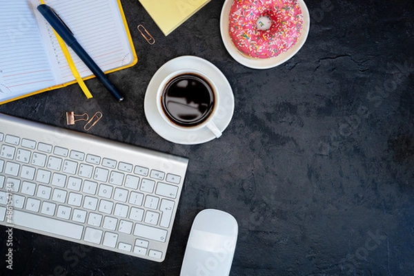 Obraz The Working Surface Of The Table. The Person Works In The Office, At Home Or In A Cafe. Brunch Or Coffee Break Time. Coffee And Donut. View From Above. Flat Lay. Dark Background. Ready For Text.