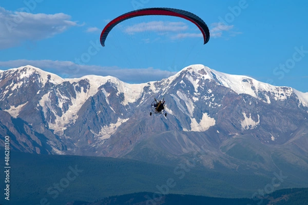 Fototapeta paraglider with a motor with two pilots on the background of Mount Aktru in the Altai mountains