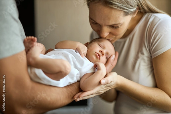 Fototapeta Portrait of happy young father hugging and kissing his adorable newborn child.
