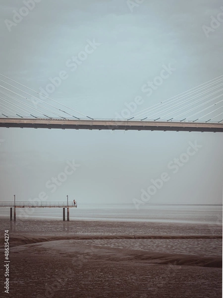 Fototapeta Person alone in the end of the pier over the river near bridge