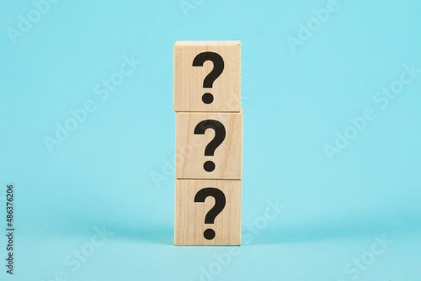 Fototapeta QUESTION The shape of a wooden cube block with a question mark symbol on a blue background. The question marks on the wooden block
