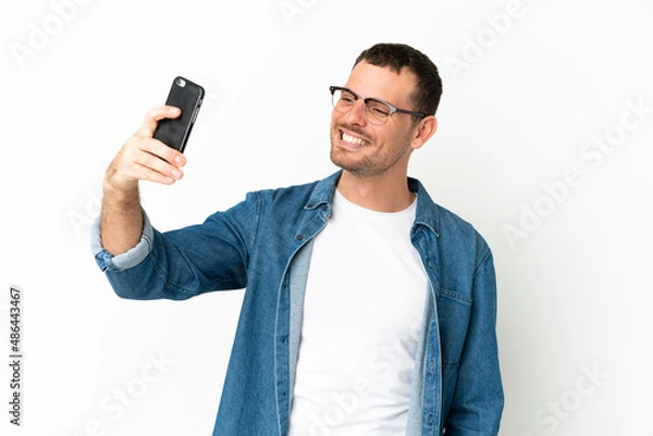 Fototapeta Brazilian man over isolated white background making a selfie