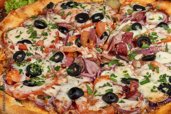 Fototapeta Pizza with bacon and cheese, herbs and cherry tomatoes. With mozzarella, shrimps and octopuses, mussels and other products on a wooden background.
