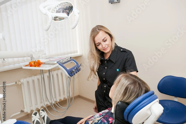 Obraz a dentist is a young white woman with blonde hair who is receiving a patient in a dental chair