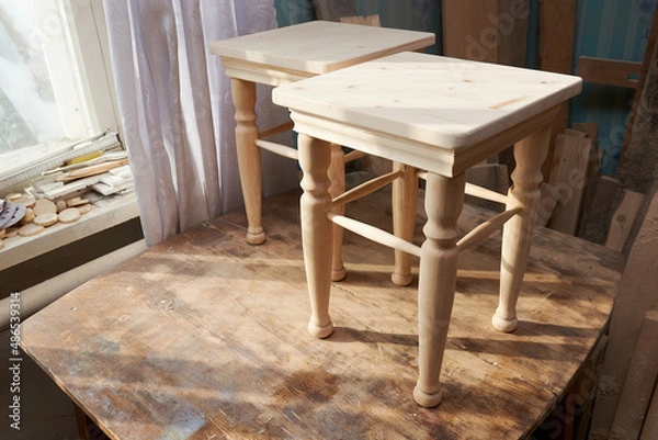 Fototapeta Stool making in woodworking workshop. Interior of the carpentry workshop in the rays of sunlight at home.