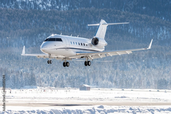 Fototapeta Luxury business jet arriving in the swiss alps. The way to travel for the rich and wealthy to their winter holidays