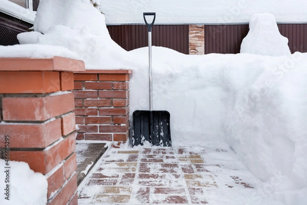 Obraz Big snow shovel is next to snowdrifts. Soft focus.Сoncept of cleaning a large amount of snow from sideway.