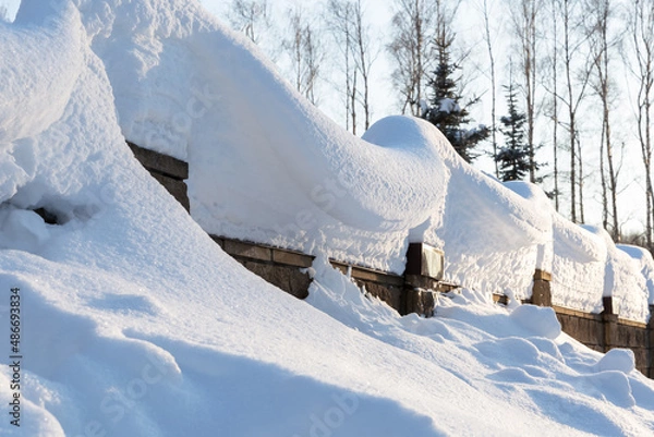 Obraz Overhanging beautifully curved snow caps on a fence in sunlight.Soft focus. Snowy winter concept.