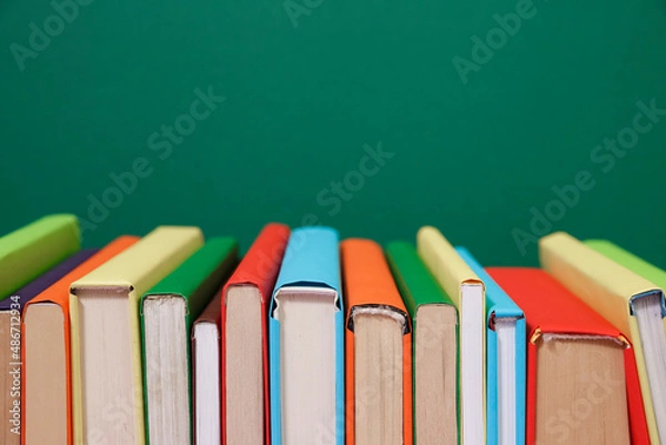 Fototapeta Composition with vintage old hardback books, diary, fanned pages on wooden deck table and colored background. Books stacking. Back to school. Copy Space. Education background.