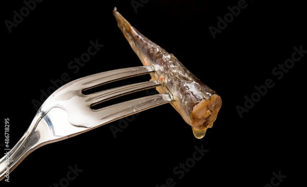 Fototapeta Galician sardine, pierced on a fork, with a black background