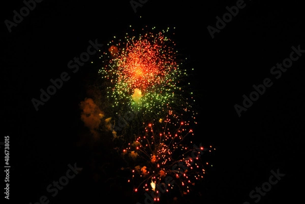 Fototapeta Colorful salute, great explodes in different colors in the night sky, beautifully dissolving in the air.