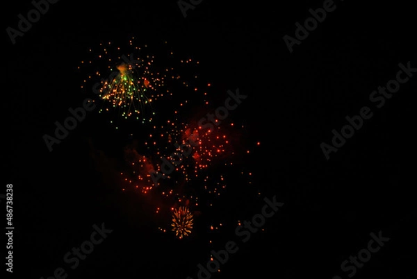Fototapeta Colorful salute, great explodes in different colors in the night sky, beautifully dissolving in the air.
