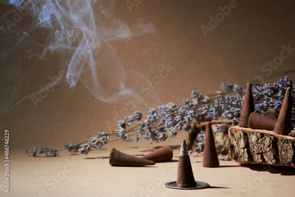 Fototapeta Incense cones for aromatherapy with lavender flowers on a brown background. Burning incense cone 