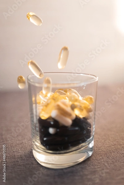 Fototapeta Vitamins and dietary supplements close-up. Macrophoto of capsules. Vitamins on the table.