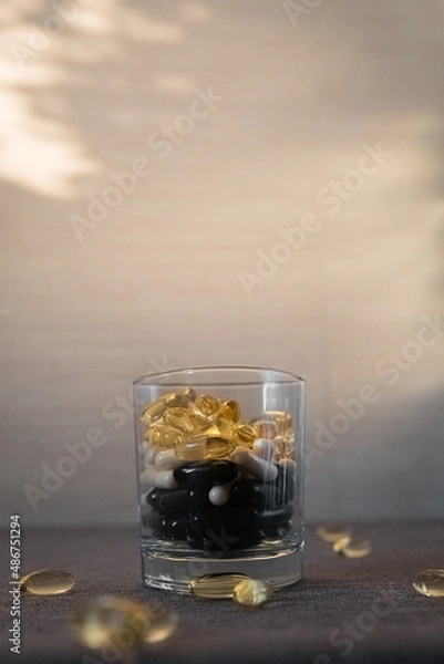Fototapeta Vitamins and dietary supplements close-up. Macrophoto of capsules. Vitamins on the table.
