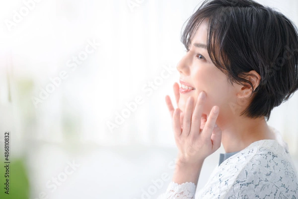 Fototapeta 上を見つめて肌に手を添える女性　コピースペースあり