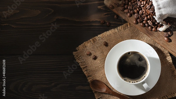 Fototapeta White cup of fresh hot coffee and coffee beans on the table, top view, flatl ay, copyspace