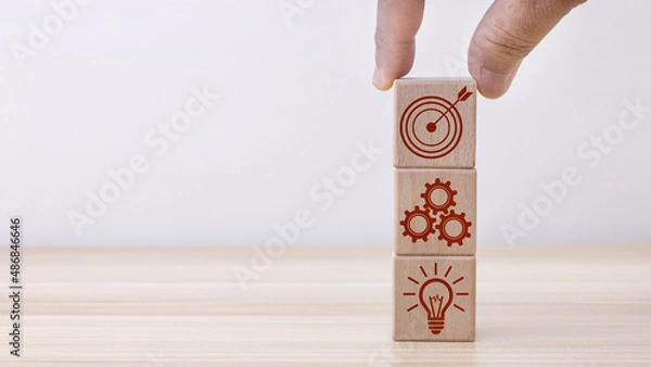 Fototapeta Concept of business strategy and action plan. Businessman hand putting wood cube block on top with icon