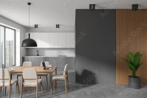 Fototapeta Grey kitchen interior with dining table and seats, window and plant. Empty wall