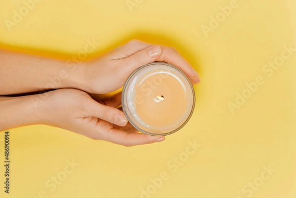 Obraz Female hands with scented candle and flowers. Aromatherapy and spa