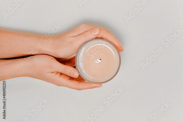Obraz Female hands with scented candle and flowers. Aromatherapy and spa