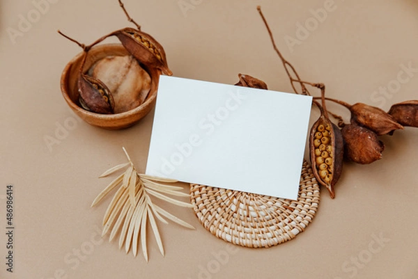 Obraz Minimal aesthetic background with blank card and dry floral branch on beige background. Wedding invitation template. Flat lay, top view, mock up, copy space ..