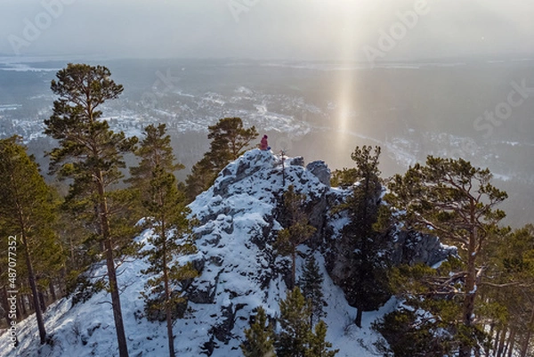 Fototapeta A tourist sits on top of a cliff and admires the views