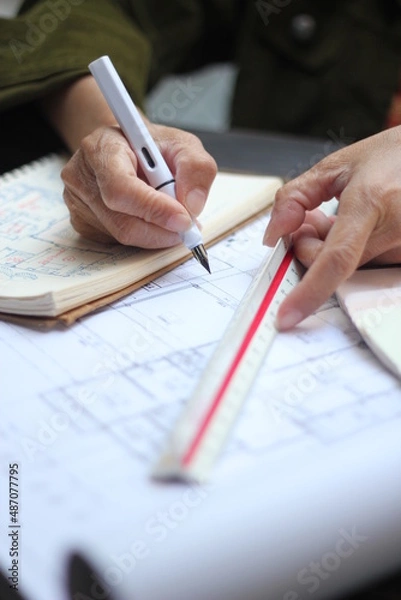 Fototapeta Hands of Asian female engineers are working on construction drawings on site.