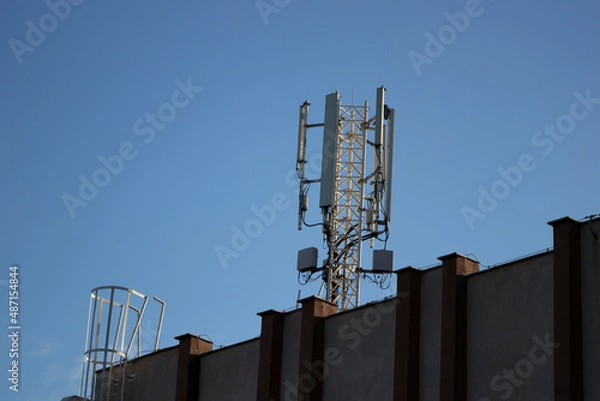 Fototapeta Telecommunication tower of 4G and 5G cellular. 5G radio network telecommunication equipment with radio modules and smart antennas mounted on a metal. Blue sky in the background. Located on the roof.