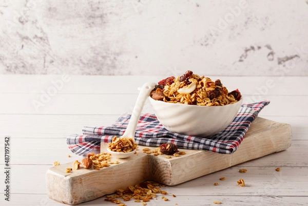 Fototapeta Granola bowl with raisins, nuts and fresh berries. Homemade crunchy granola on grey concrete background, top view
