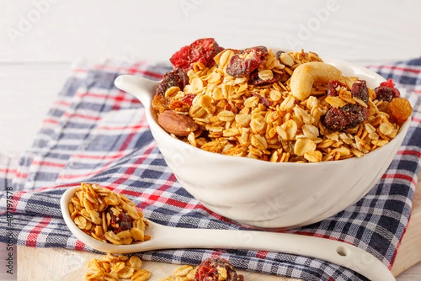 Fototapeta Granola bowl with raisins, nuts and fresh berries. Homemade crunchy granola on grey concrete background, top view