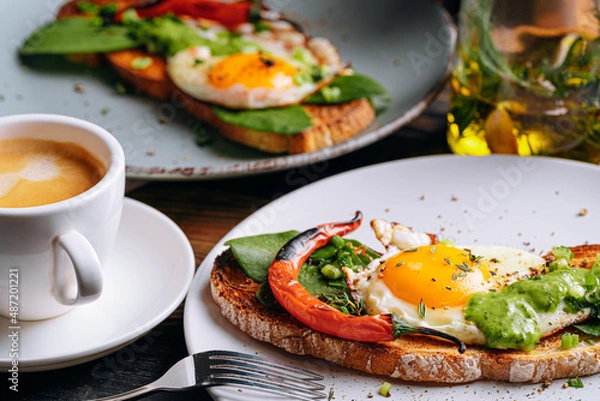 Fototapeta hearty and high-calorie breakfast. delicious and mouth-watering bruschetta with fried eggs and herbs for breakfast with a cup of aromatic coffee.