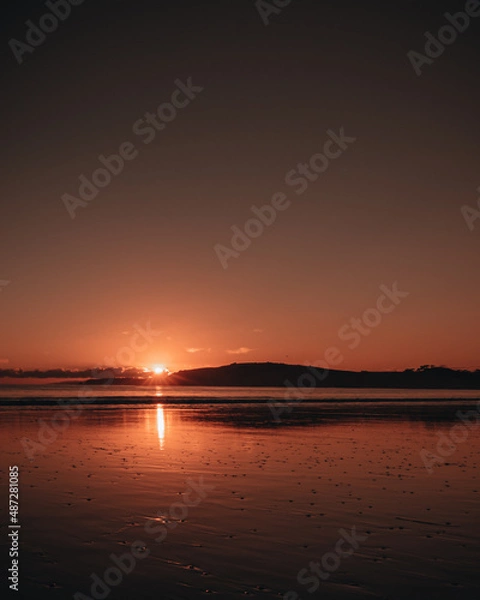 Obraz Omaha Beach with a red sunset and reflection on the ocean shore