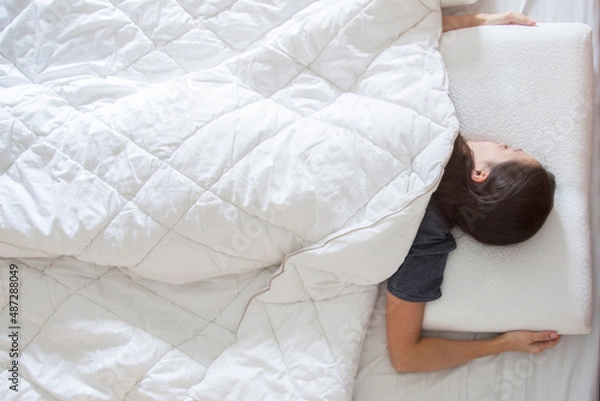 Fototapeta woman sleeping on white thin memory foam pillow on white bedsheets in the morning light