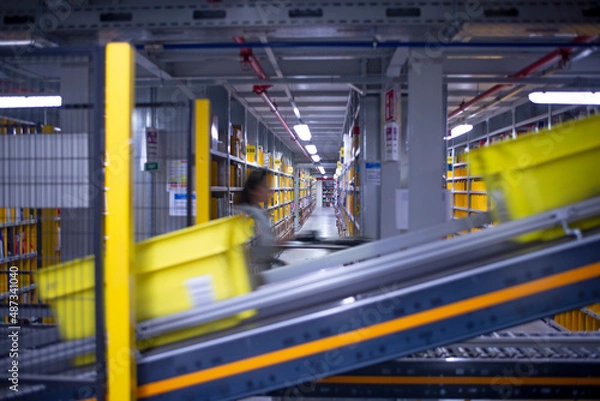 Fototapeta interior of logistic warehouse with a worker walking