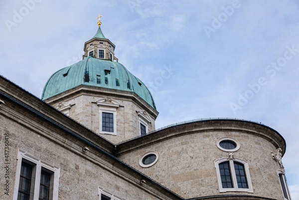 Fototapeta Salzburg, Austria, 28 August 2021: Baroque cathedral with bell and clock white tower at Domplatz square at summer day, green copper dome