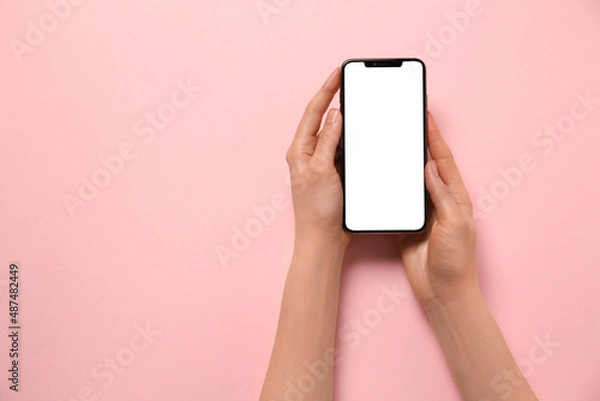 Fototapeta Woman with smartphone on pink background, top view. Space for text