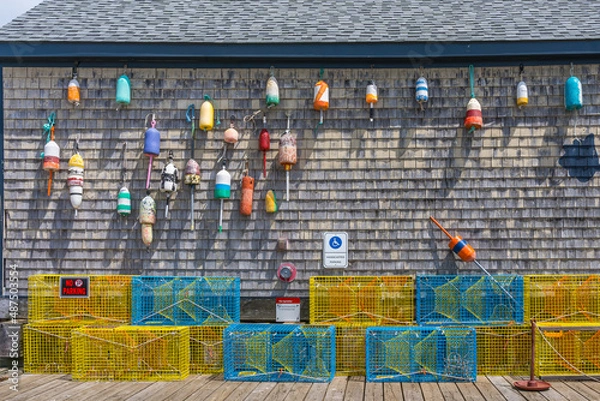 Obraz The gray plank wall of a traditional home is adorned with old floats and lobster traps as a symbol of a New England fishing village by the Atlantic Ocean.