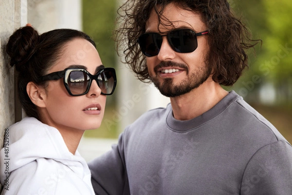 Obraz loving couple in sunglasses is walking down the street. A pair of loving young people looking at the camera