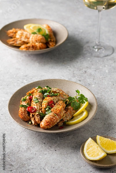 Fototapeta Grilled shrimp with lemon and herbs butter sauce. Spiked shrimp-bear on a plate with a glass of white wine. Bering shrimp. Menu concept for restaurants